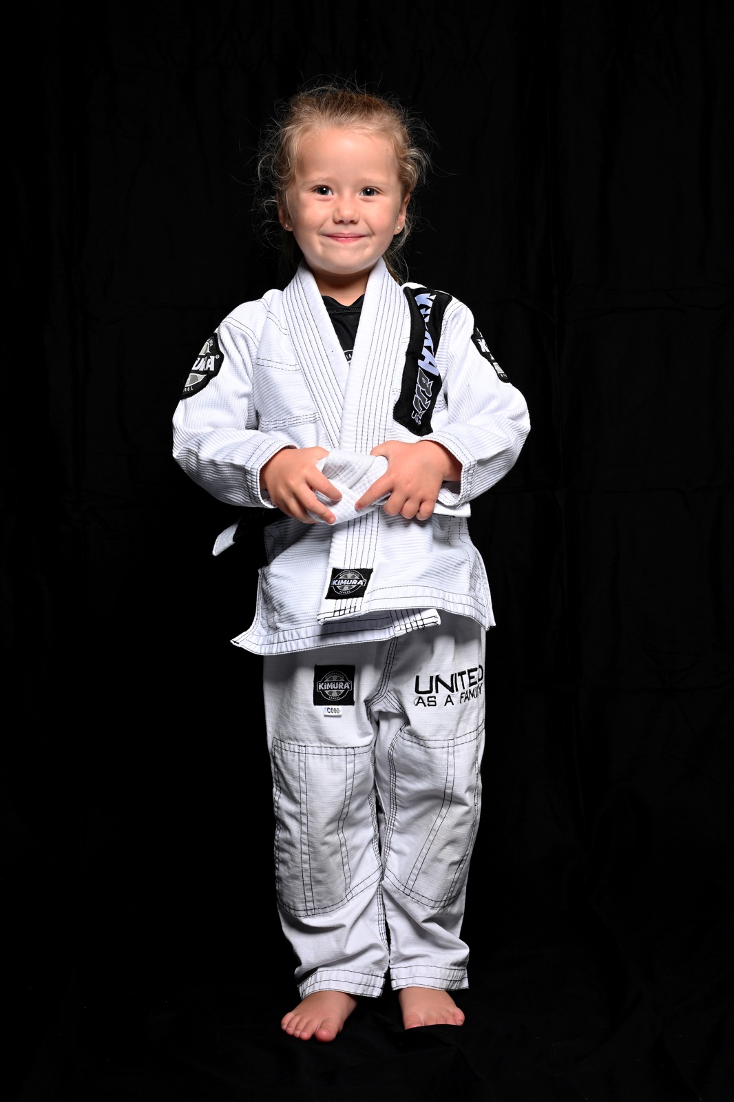 A young martial artist posing in a white Jiu-Jitsu gi