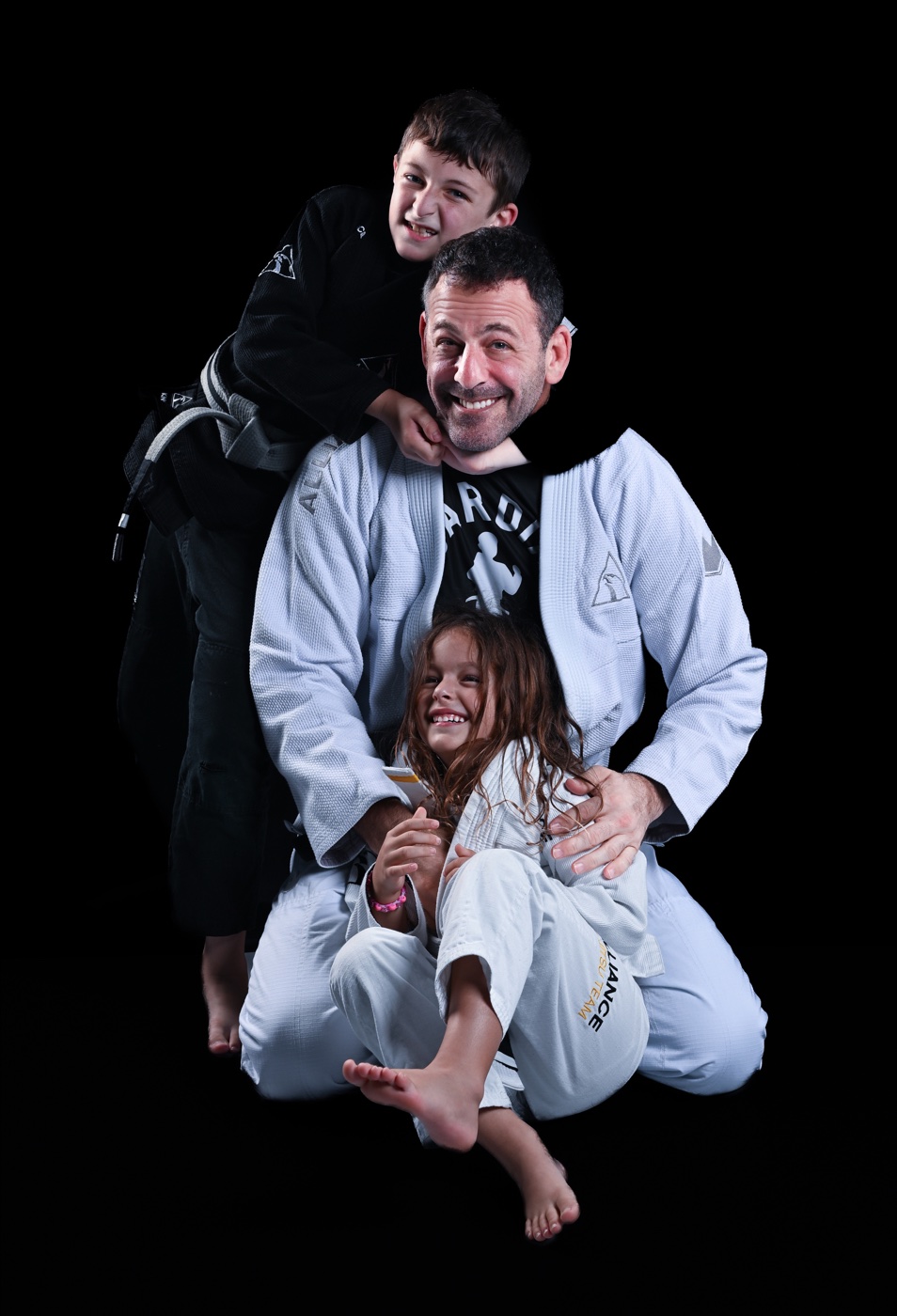 A father and two children posing together in Jiu-Jitsu gis