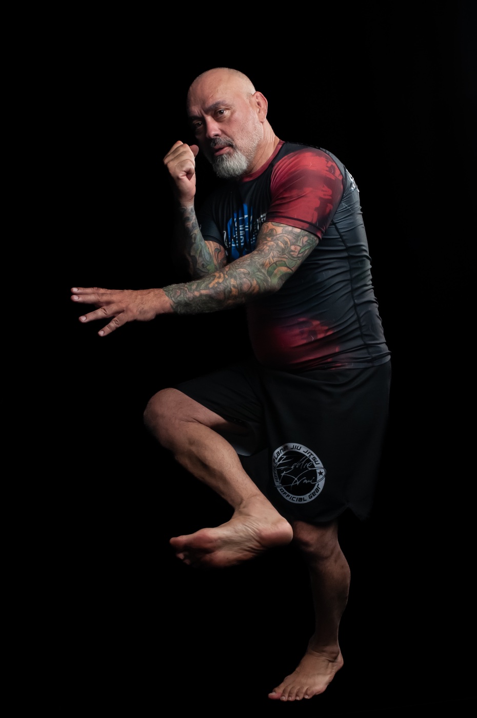 Martial artist balancing in a fighting stance against a black studio backdrop